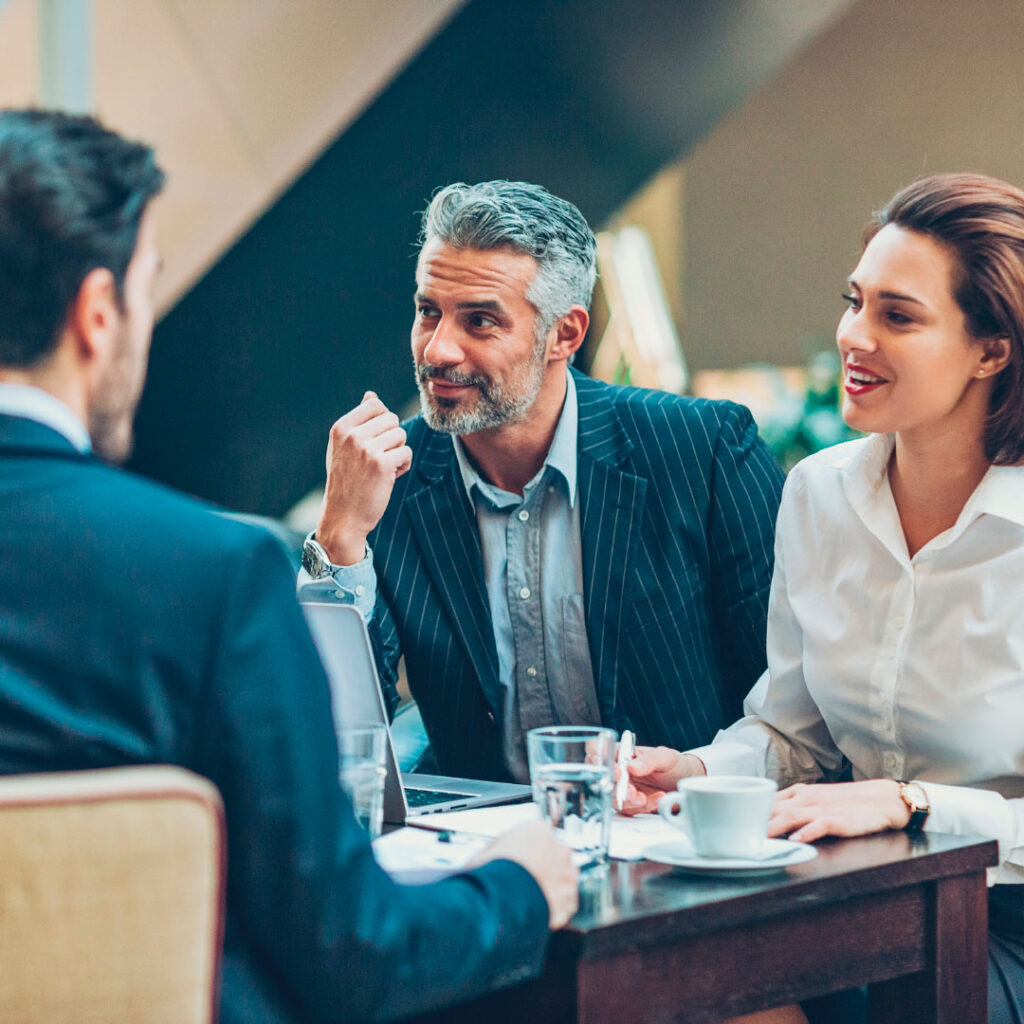 two men and a woman sat at a table discussing business formation